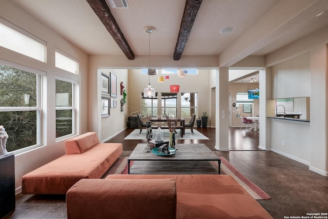 living room featuring beam ceiling, a wealth of natural light, and sink