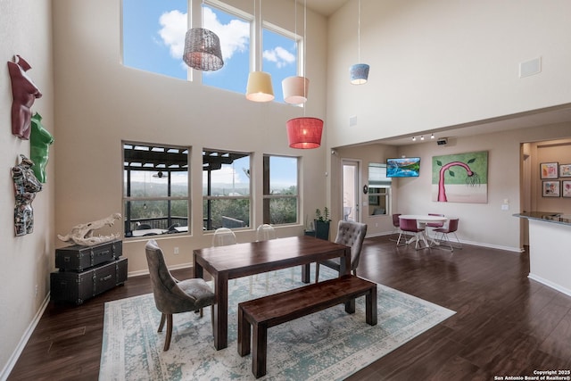 dining area featuring a towering ceiling and dark hardwood / wood-style flooring