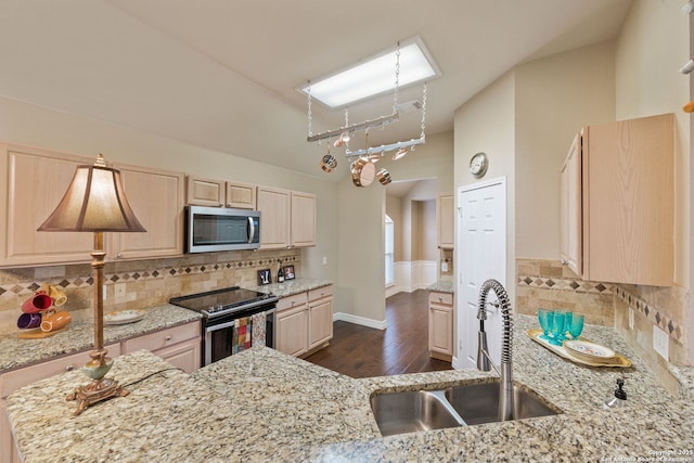 kitchen with light brown cabinets, stainless steel appliances, decorative backsplash, sink, and light stone counters