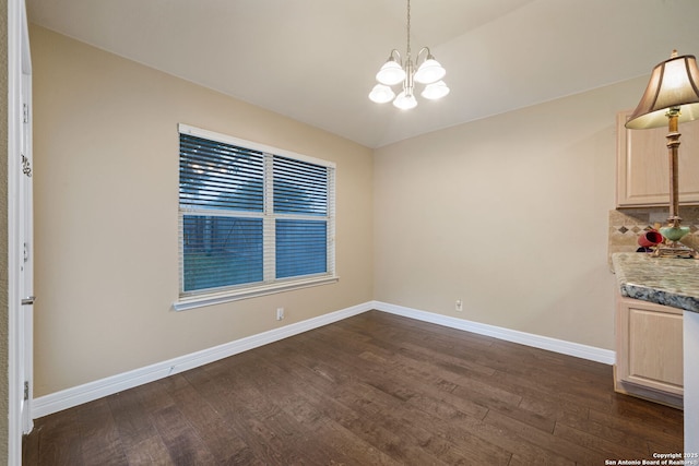 unfurnished dining area with dark wood-type flooring and an inviting chandelier