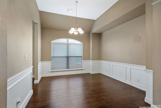 empty room with dark wood-type flooring, lofted ceiling, and a notable chandelier