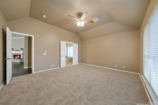 unfurnished bedroom with ceiling fan, vaulted ceiling, a fireplace, and carpet floors