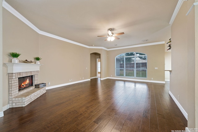 unfurnished living room with ceiling fan, ornamental molding, dark hardwood / wood-style flooring, and a brick fireplace