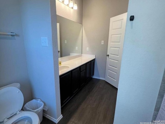 bathroom featuring toilet, wood-type flooring, and vanity