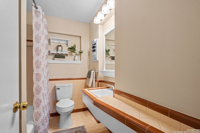 bathroom featuring tile walls, curtained shower, sink, and toilet