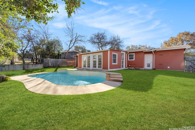 view of swimming pool with french doors, a yard, and an outbuilding