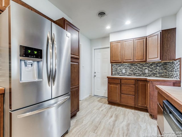 kitchen featuring tasteful backsplash, dishwasher, and stainless steel refrigerator with ice dispenser