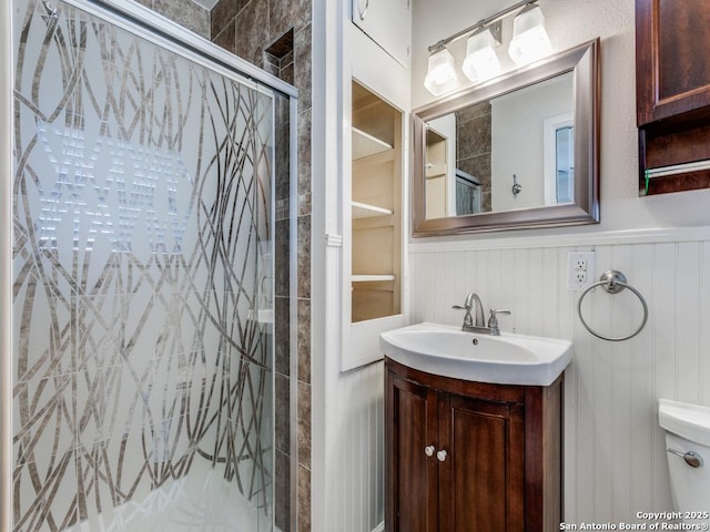 bathroom featuring toilet, an enclosed shower, and vanity