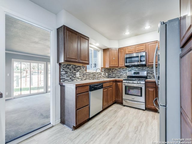 kitchen featuring ornamental molding, stainless steel appliances, and sink