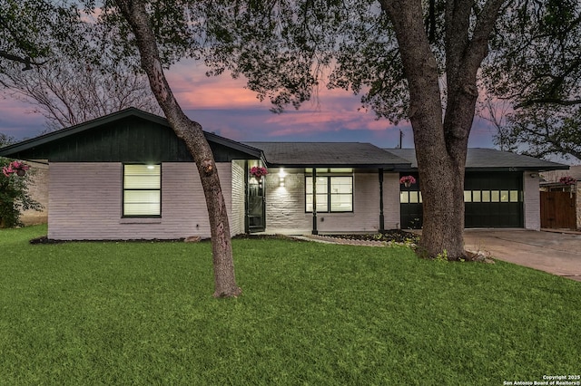 view of front of property with an attached garage, brick siding, driveway, and a front lawn