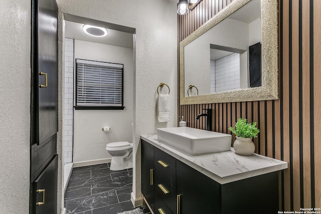 bathroom with marble finish floor, toilet, vanity, and baseboards