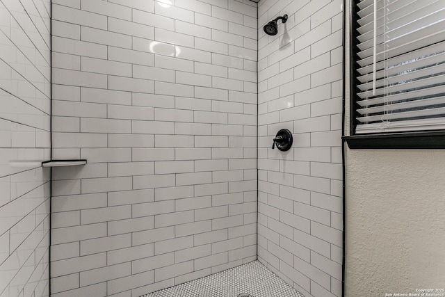 bathroom featuring tiled shower and a textured wall