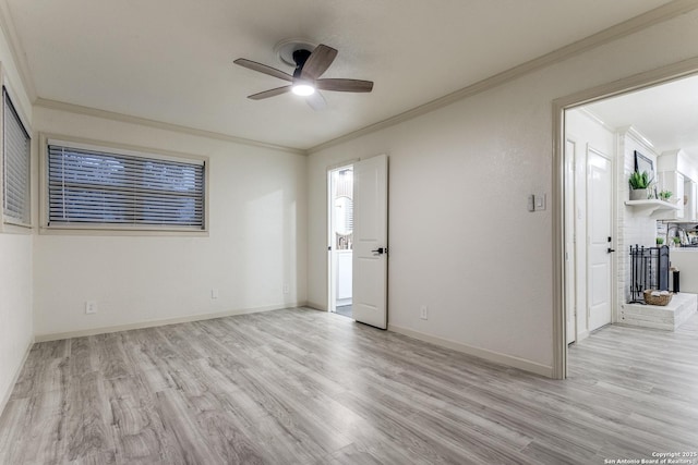 spare room with a fireplace, ornamental molding, ceiling fan, and light wood-type flooring