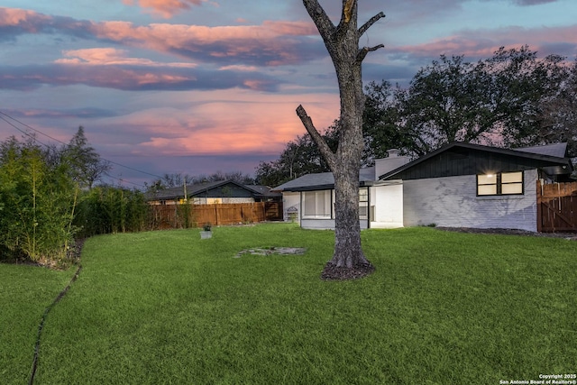 yard at dusk featuring fence