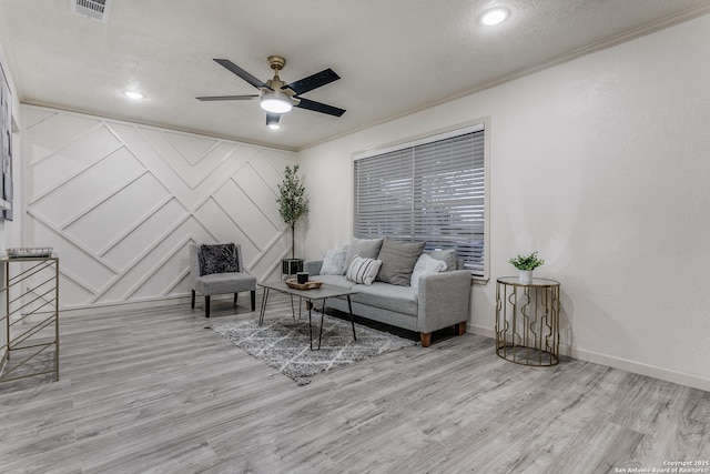 living room featuring light wood-type flooring, ceiling fan, and ornamental molding