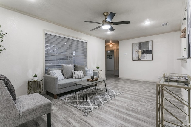 living room with a textured ceiling, ceiling fan, ornamental molding, and light hardwood / wood-style flooring