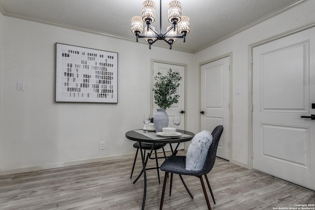 dining area with light wood-type flooring, a textured ceiling, a notable chandelier, and crown molding