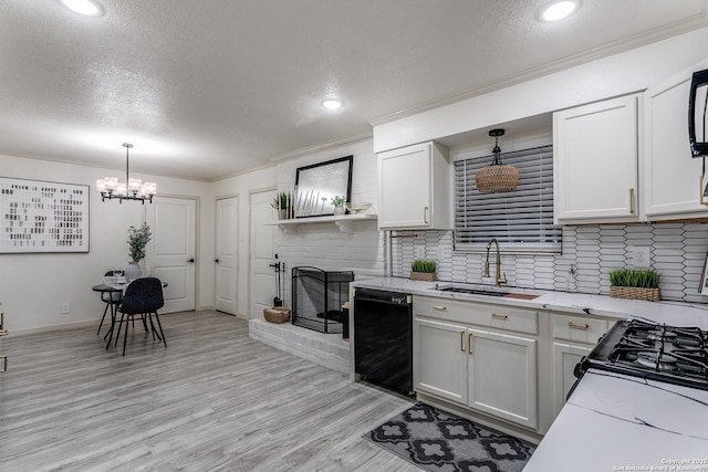 kitchen with a fireplace, tasteful backsplash, light wood-style flooring, a sink, and dishwasher