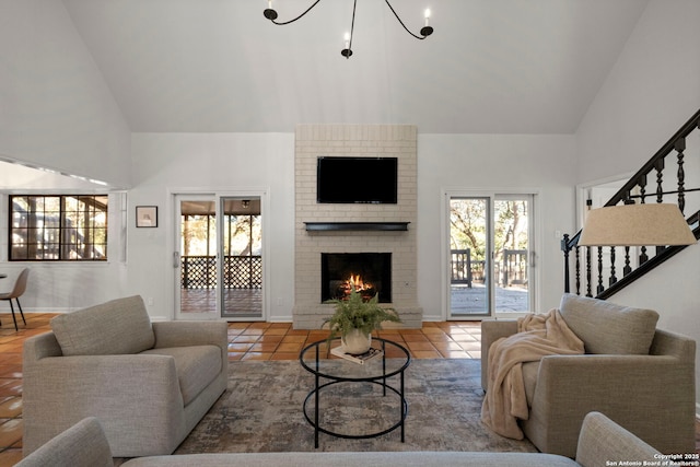 tiled living room with high vaulted ceiling, a fireplace, and an inviting chandelier