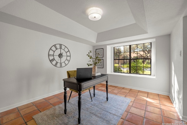 home office featuring a tray ceiling and light tile patterned floors