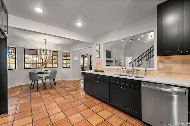 kitchen featuring stainless steel dishwasher, hanging light fixtures, light tile patterned floors, decorative backsplash, and sink