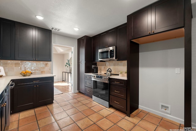 kitchen featuring appliances with stainless steel finishes, light tile patterned flooring, and decorative backsplash