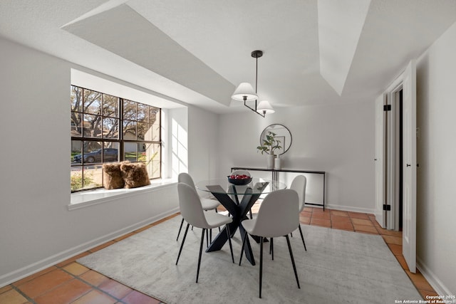 tiled dining area with a raised ceiling