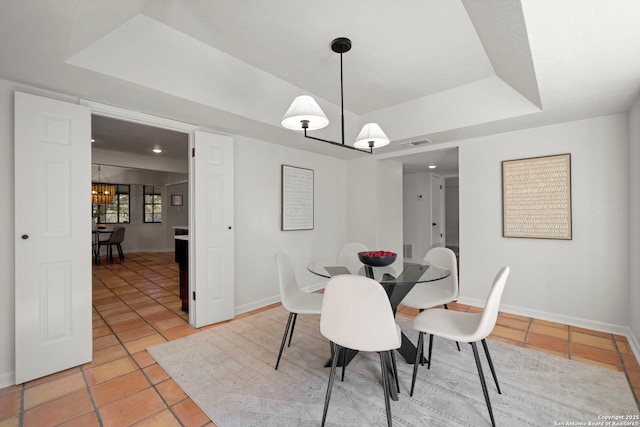 tiled dining area featuring a notable chandelier and a tray ceiling