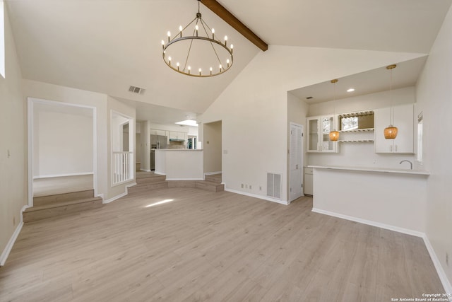 unfurnished living room with a notable chandelier, light wood-type flooring, high vaulted ceiling, and beamed ceiling