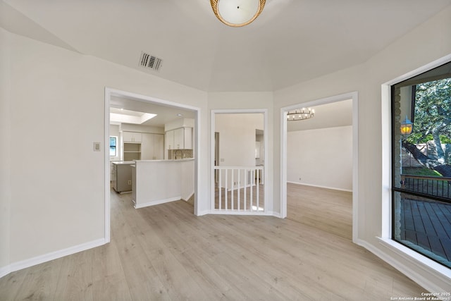 unfurnished room featuring a chandelier and light wood-type flooring