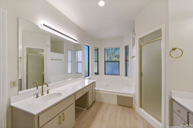 bathroom featuring hardwood / wood-style floors, shower with separate bathtub, and vanity