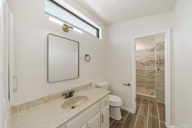 bathroom with a tile shower, vanity, and toilet