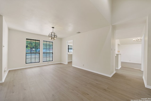 empty room featuring light hardwood / wood-style flooring and an inviting chandelier