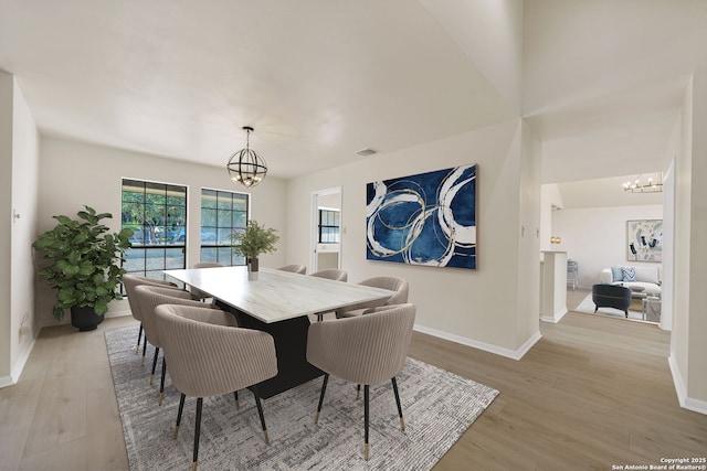 dining area with light wood-type flooring and a chandelier