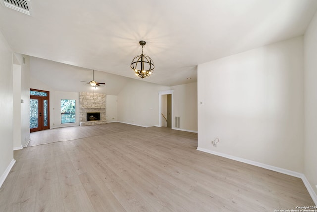 unfurnished living room featuring lofted ceiling, ceiling fan with notable chandelier, a fireplace, and light hardwood / wood-style flooring