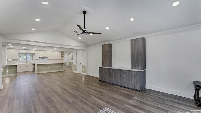 unfurnished living room with dark hardwood / wood-style flooring, ceiling fan, vaulted ceiling, and ornamental molding