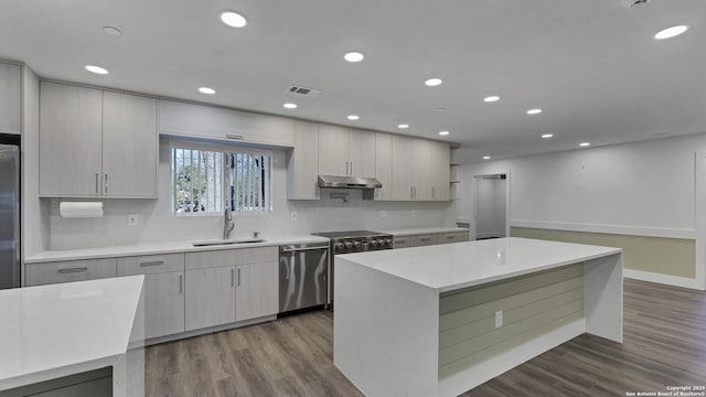 kitchen with a center island, stainless steel appliances, tasteful backsplash, hardwood / wood-style floors, and sink