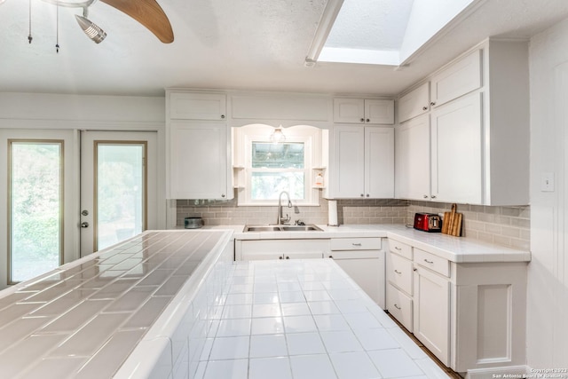 kitchen featuring sink, tile counters, white cabinetry, and tasteful backsplash