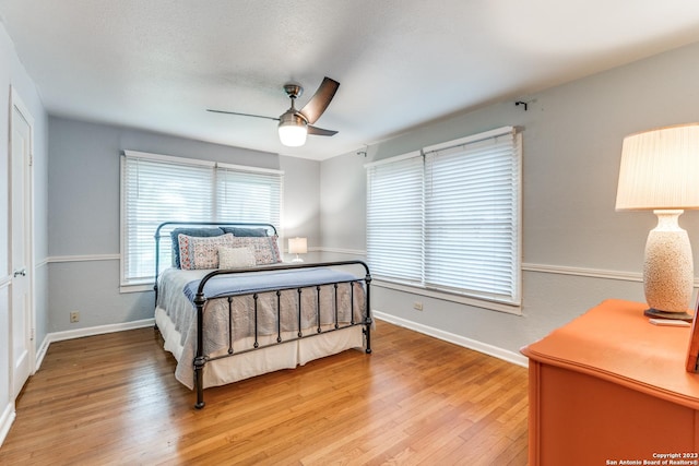 bedroom with multiple windows, ceiling fan, and light wood-type flooring