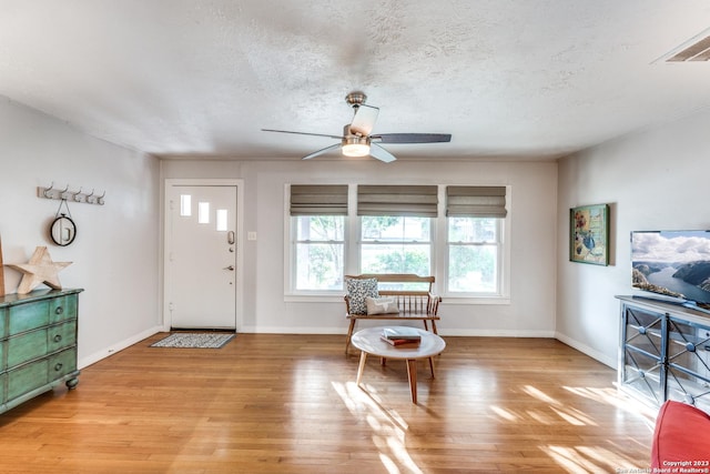 entryway with a textured ceiling, light wood-type flooring, and ceiling fan