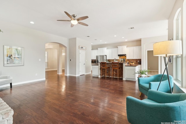 living room with arched walkways, recessed lighting, visible vents, baseboards, and dark wood-style floors