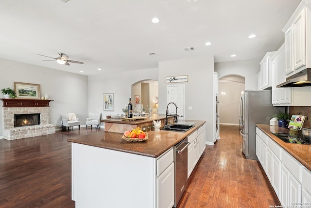 kitchen with stainless steel appliances, dark wood-type flooring, a fireplace, a sink, and white cabinetry