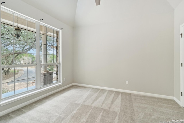 empty room featuring vaulted ceiling, carpet, and baseboards