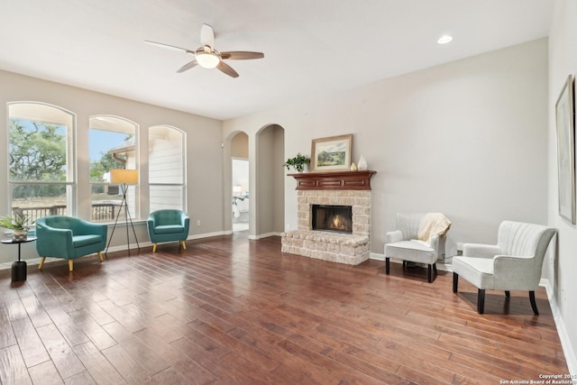 unfurnished room featuring ceiling fan, wood-type flooring, and a stone fireplace