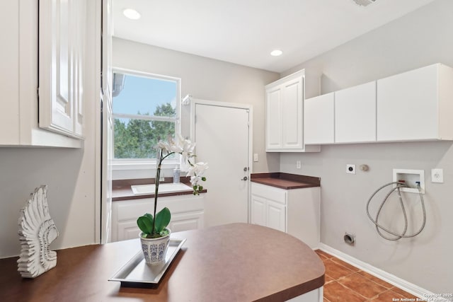 laundry area with electric dryer hookup, hookup for a washing machine, cabinets, and tile patterned floors