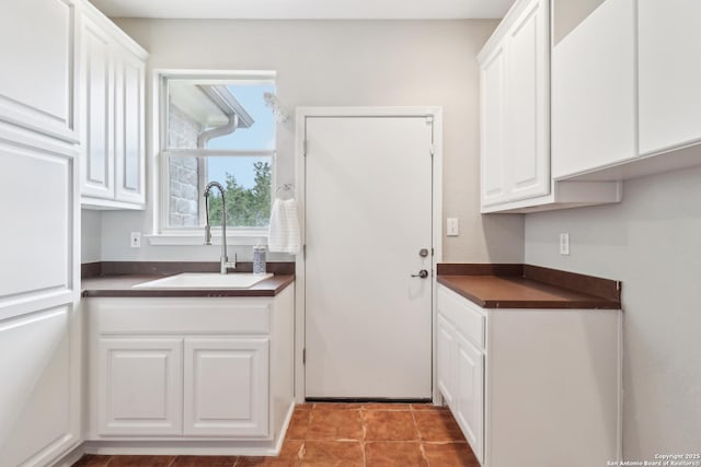 kitchen with dark countertops, a sink, and white cabinets