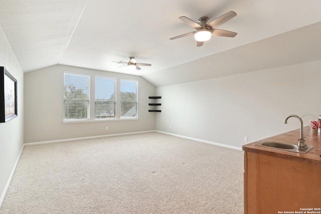 additional living space with ceiling fan, vaulted ceiling, light carpet, and sink