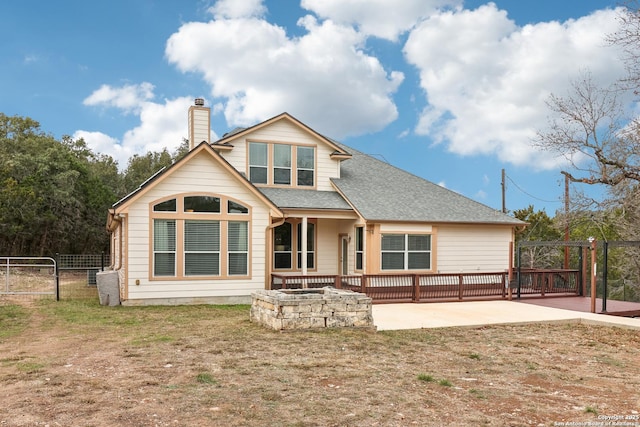 back of property with a patio, fence, roof with shingles, a gate, and a chimney