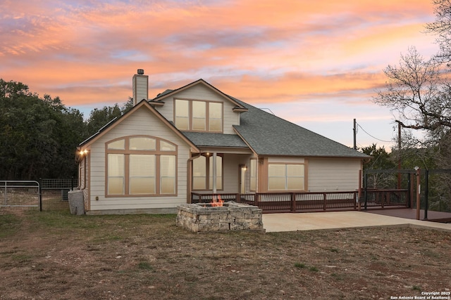 back of property featuring a fire pit, fence, a gate, a chimney, and a patio area