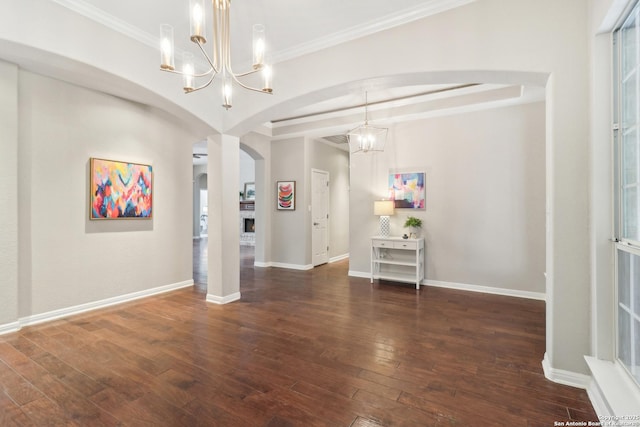 unfurnished room featuring arched walkways, wood-type flooring, an inviting chandelier, ornamental molding, and baseboards